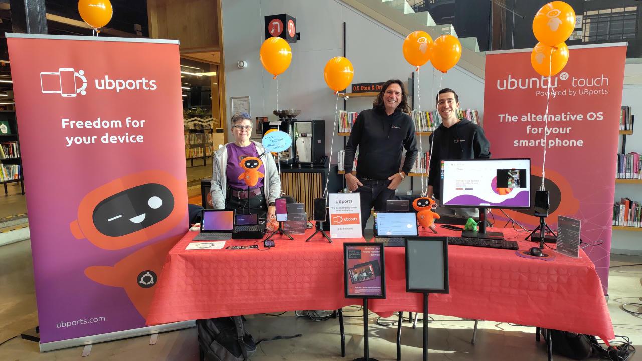 Community members standing around, showing off Ubuntu Touch on different devices.