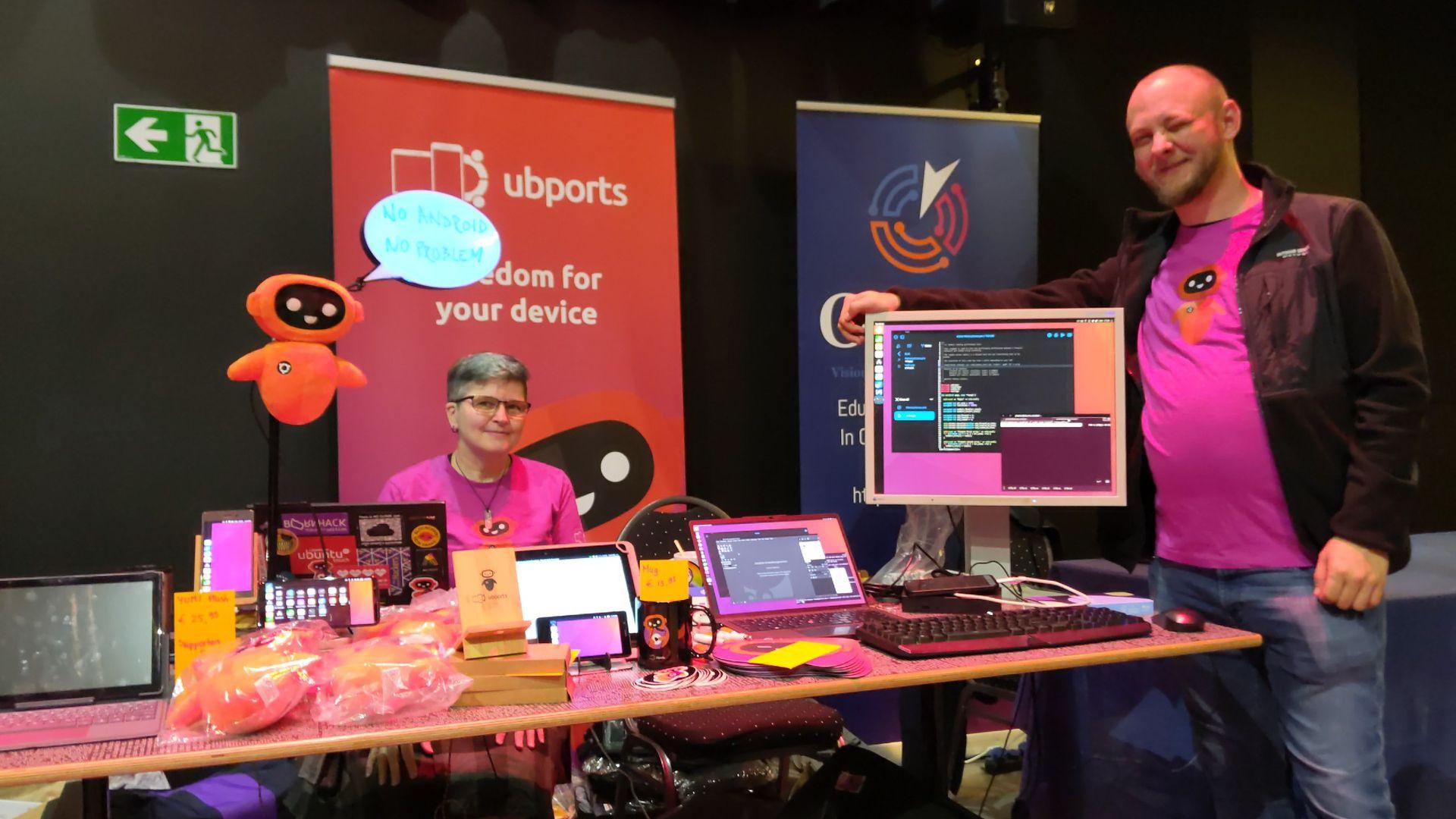 Another image of community members standing around, showing off Ubuntu Touch on different devices.